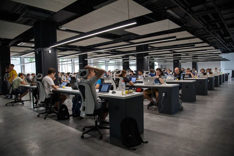 office filled with employees working on their laptops