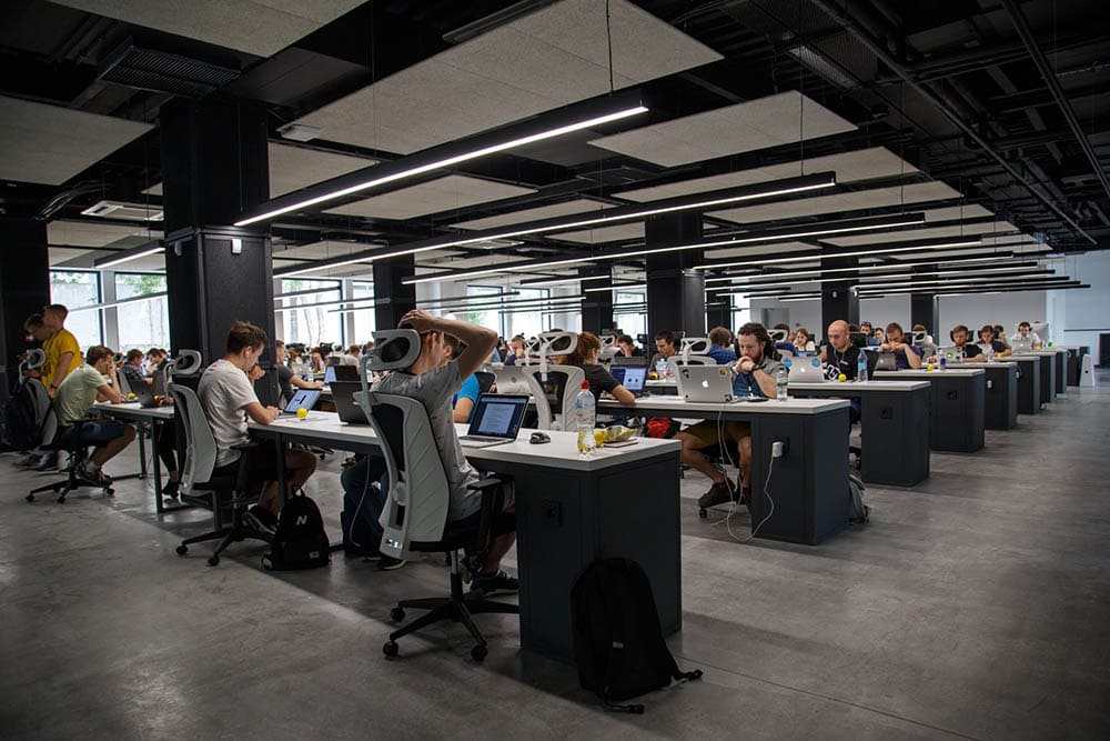 office filled with employees working on their laptops