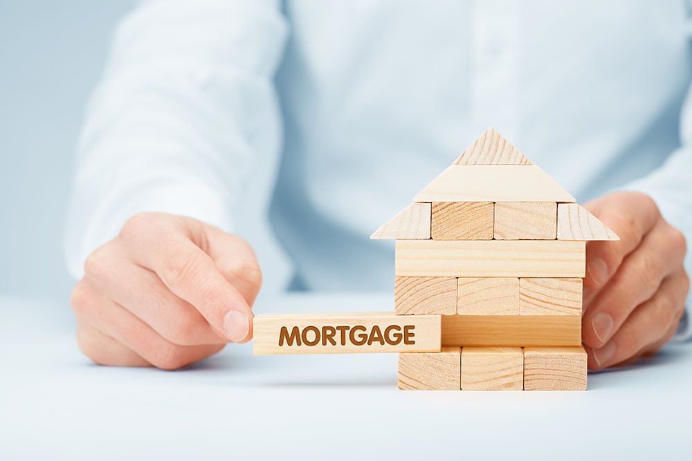 person holding wooden blocks with mortgage text