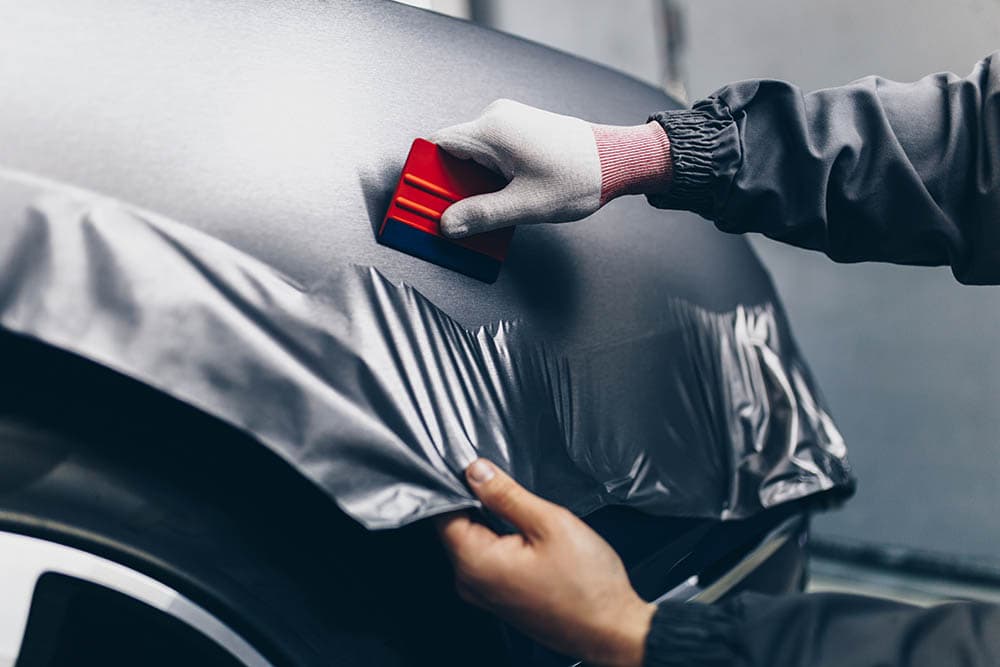 person wrapping car with vinyl film