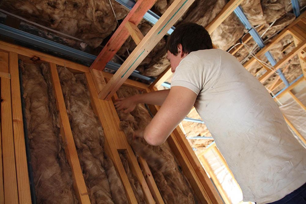 young man putting rock wool on the walls