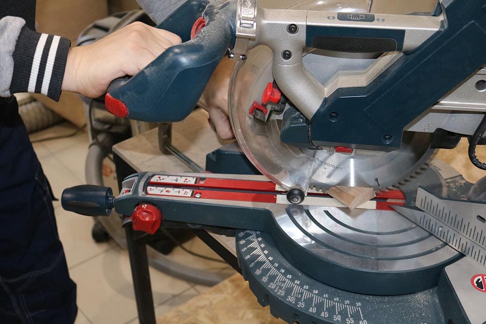 close up person using miter saw