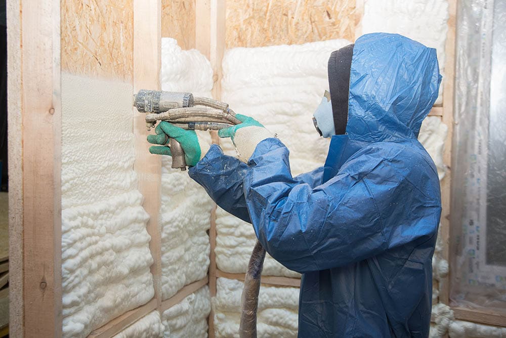 man applying spray foam insulation on the walls