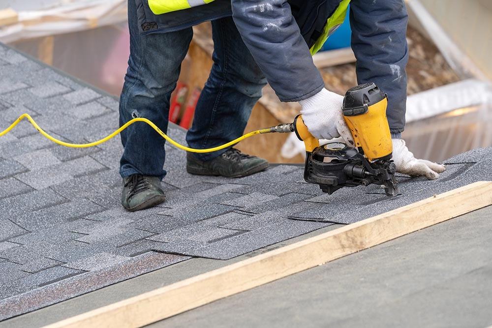 man installing asphalt shingles