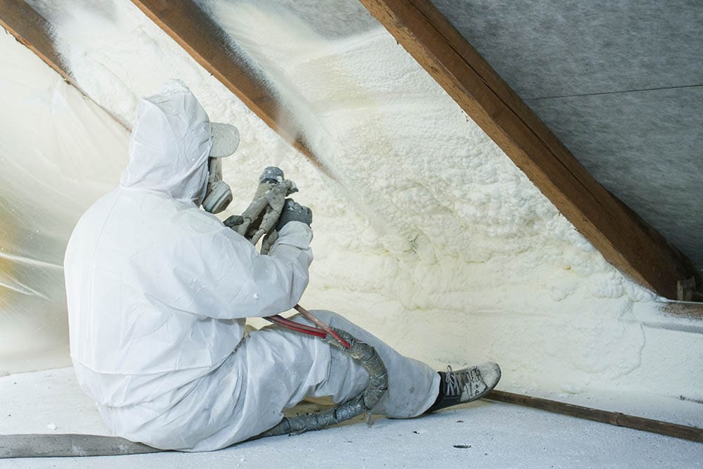 person applying spray foam insulation in the attic