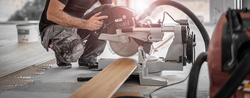 person cutting wood plank using chop saw