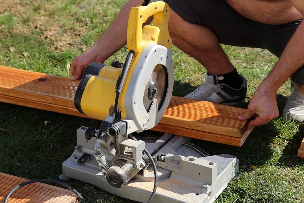 person cutting wood using chop saw