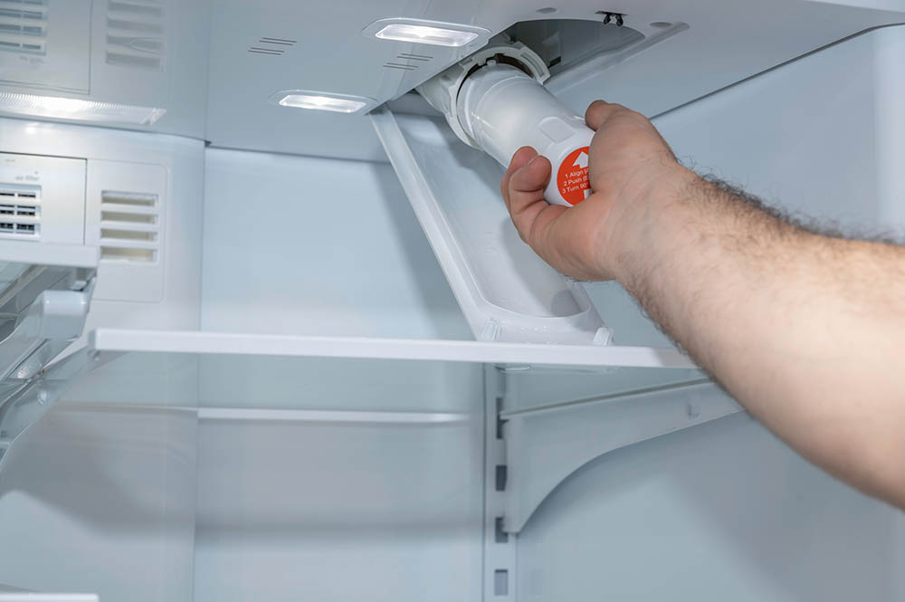 person replacing fridge water filter