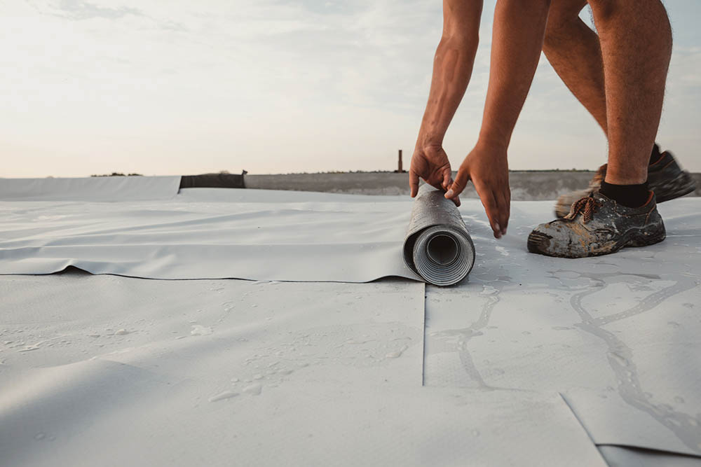 person rolling TPO roofing for installation