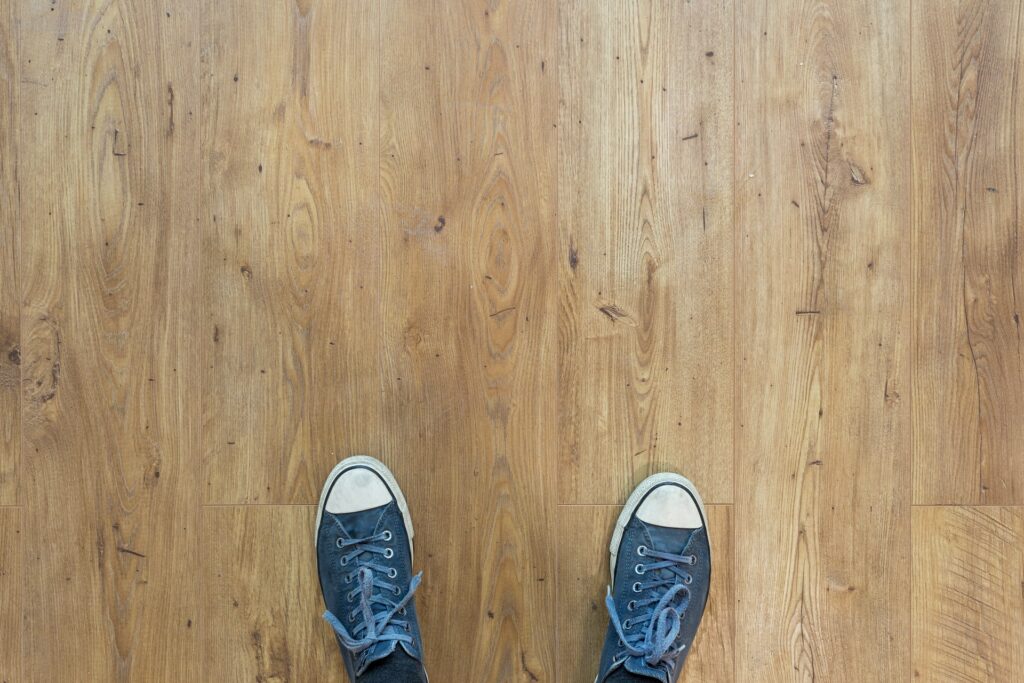 person wearing blue and white sneakers on a wood floor