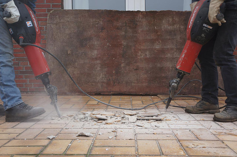 two men removing flooring with jackhammer