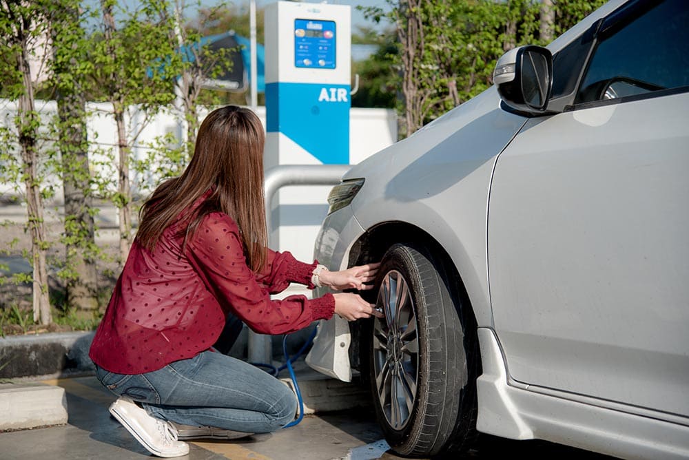 woman inflating car tire at the gas station