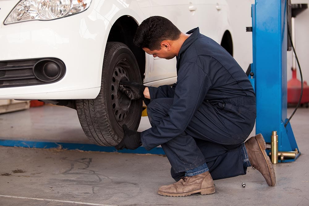 Young mechanic rotating car tires