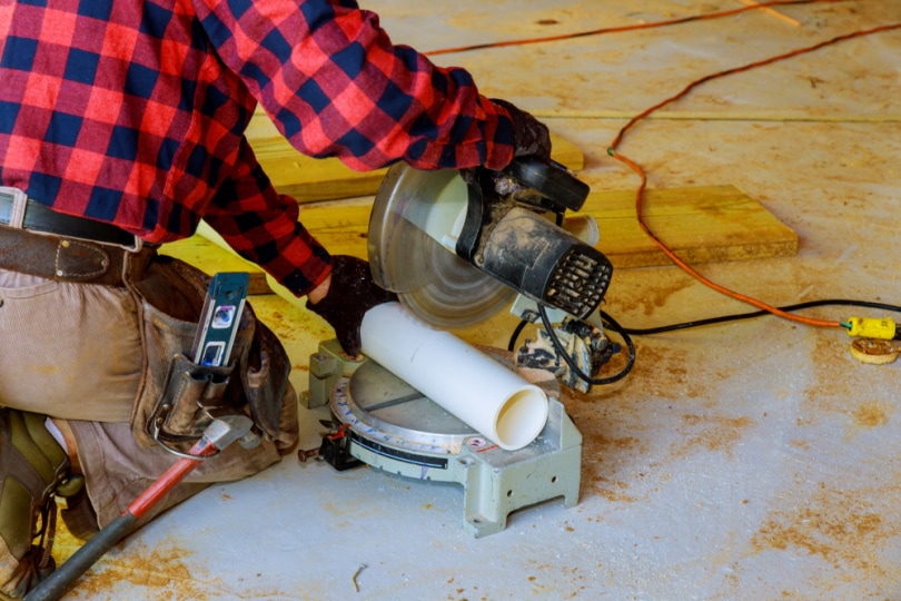 man cutting PVC pipe with saw