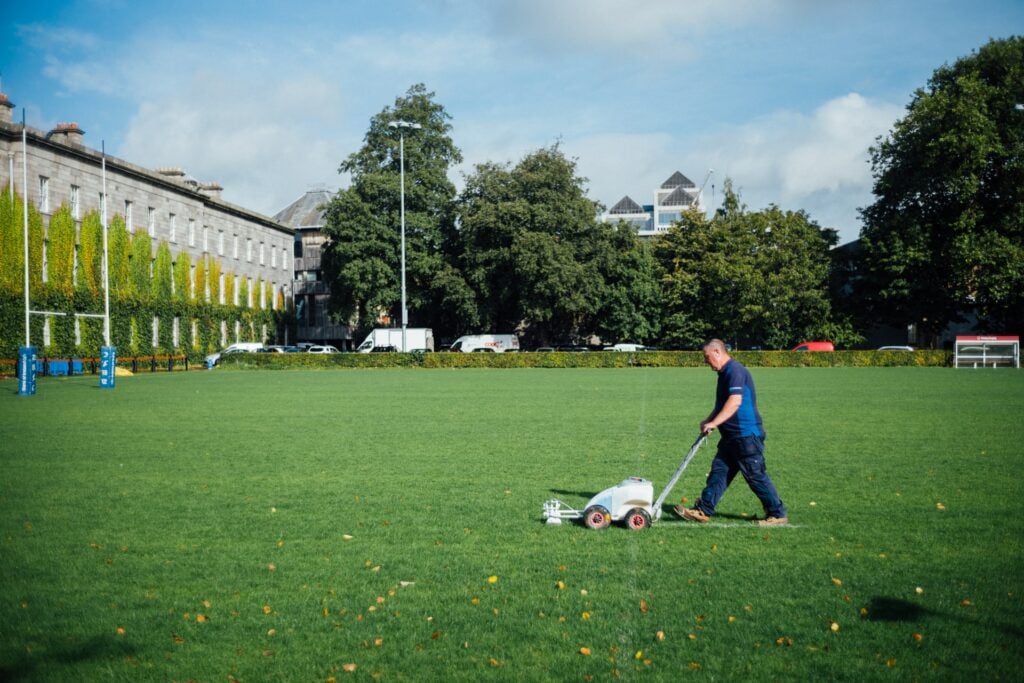 man in blue shirt mowing a lawn