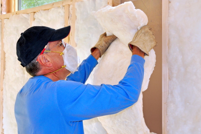 man installing fiber glass insulation