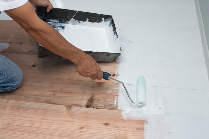 man painting a wooden floor white