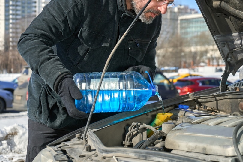 man pouring wiper fluid