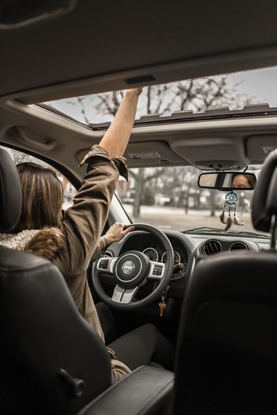 woman enjoying the sunroof of Jeep Compass
