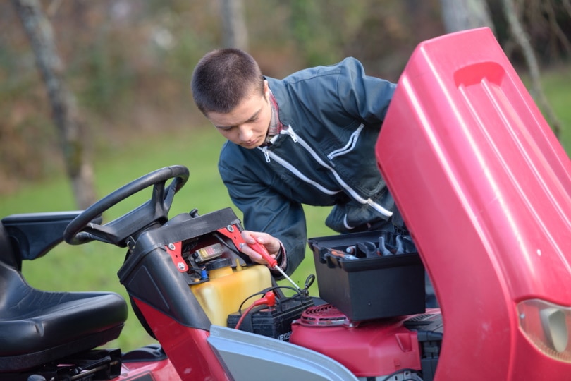 man checking lawn mower battery