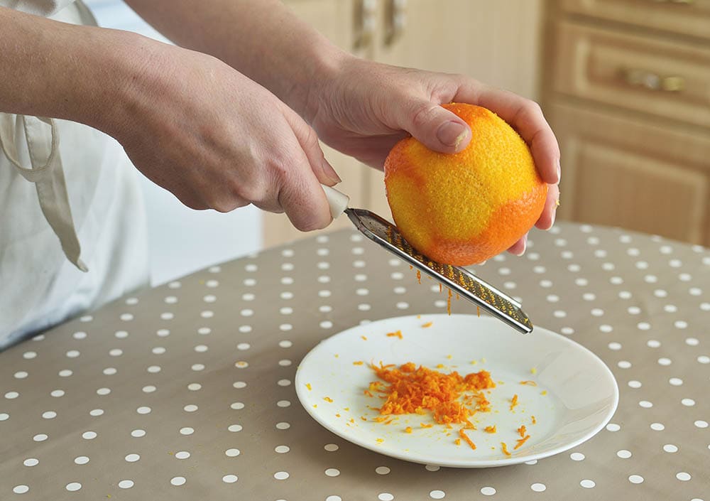 rubbing orange zest on grater_Sergey Nesterchuk_Shutterstock