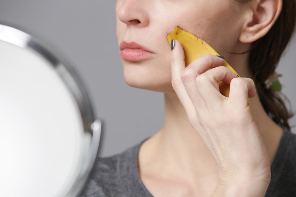 woman rubbing banana peel on face