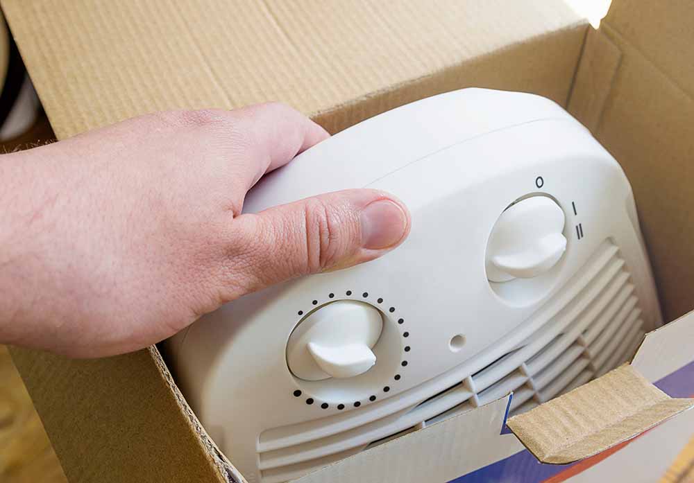 A man unpacks a box with a domestic electric heater