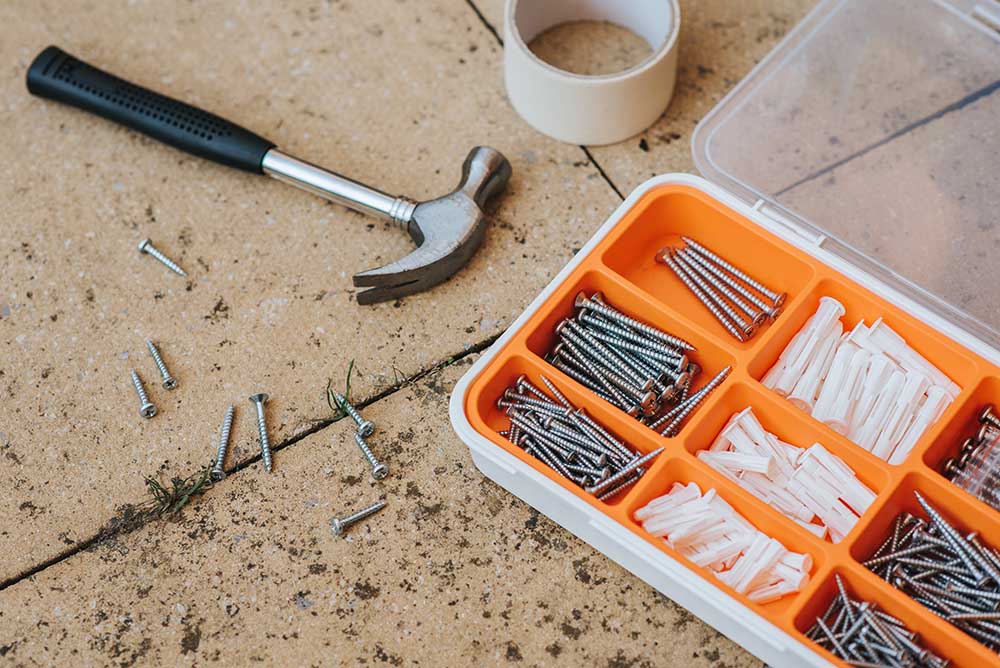 Screws and repair tools in box near a hammer