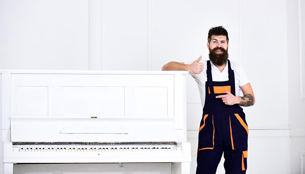 bearded man leaning on the piano with thumbs up