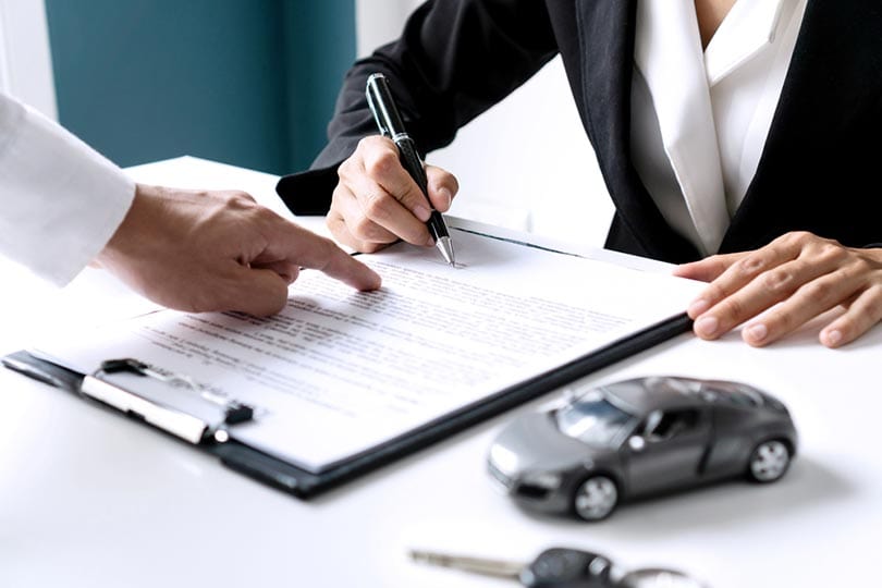 female signing car insurance document