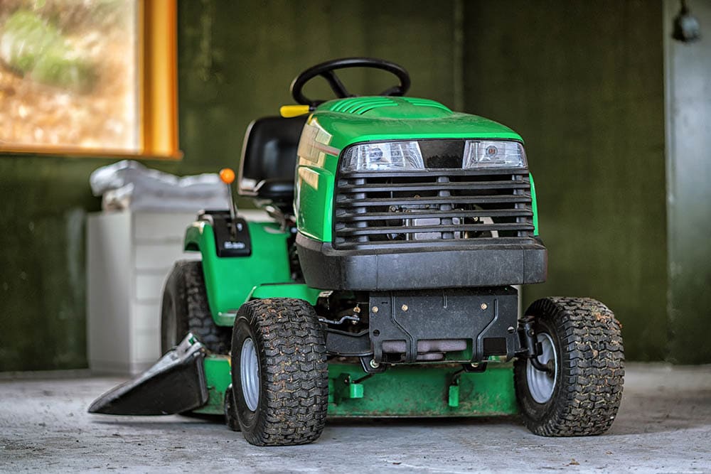 Green lawn mower inside a garage
