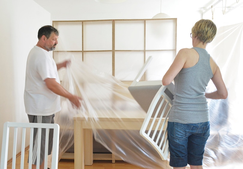 man and woman covering furniture with plastic