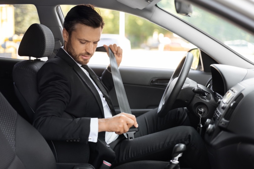 man fasten seatbelt in his car