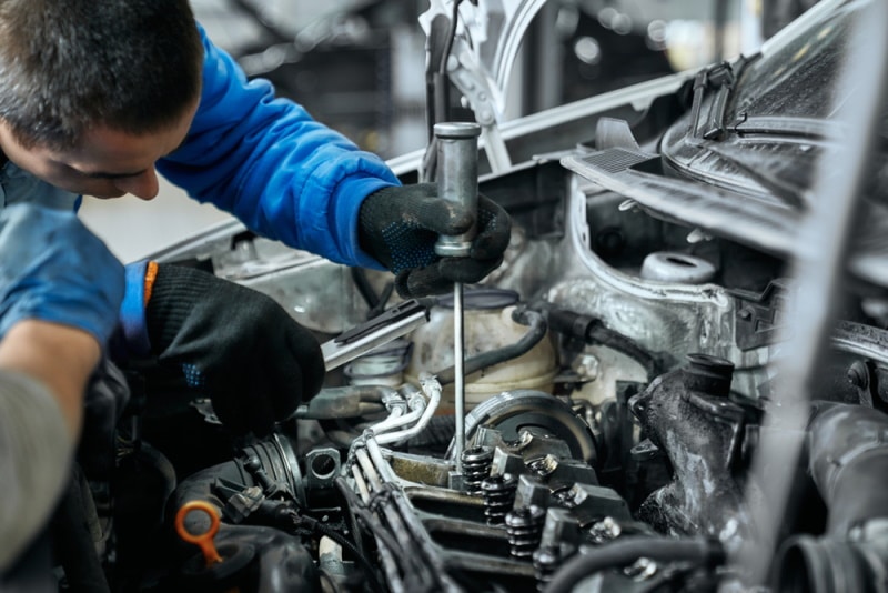 mechanic replacing glow plug in diesel engine