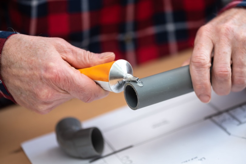 plumber putting glue on PVC pipe