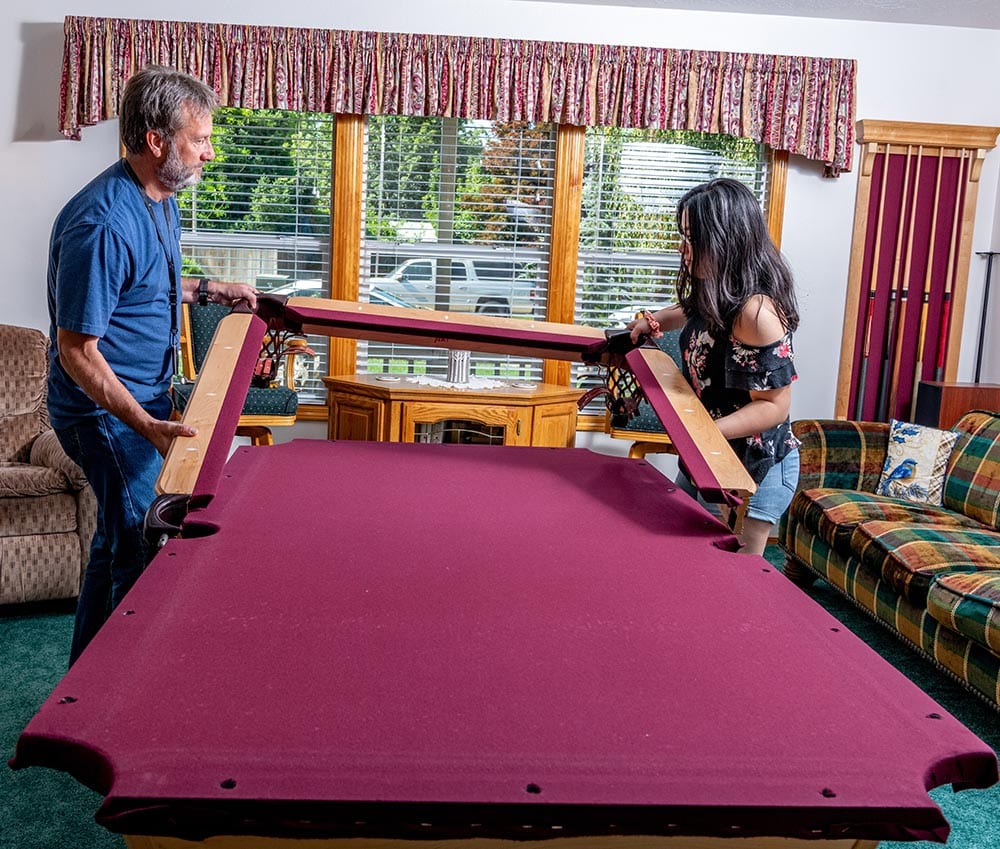 two people taking pool table apart