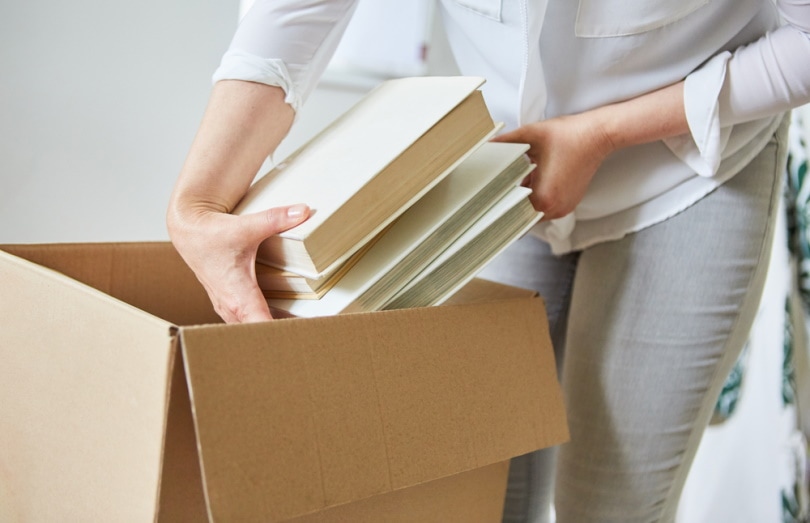 woman packs books in a box