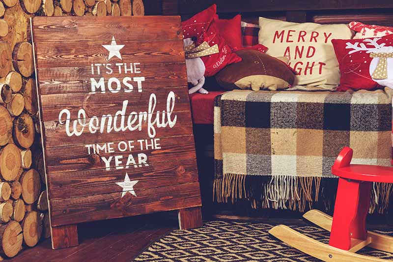 Beautiful Christmas interior design. Sofa with warm rug and pillows, near the board with sign