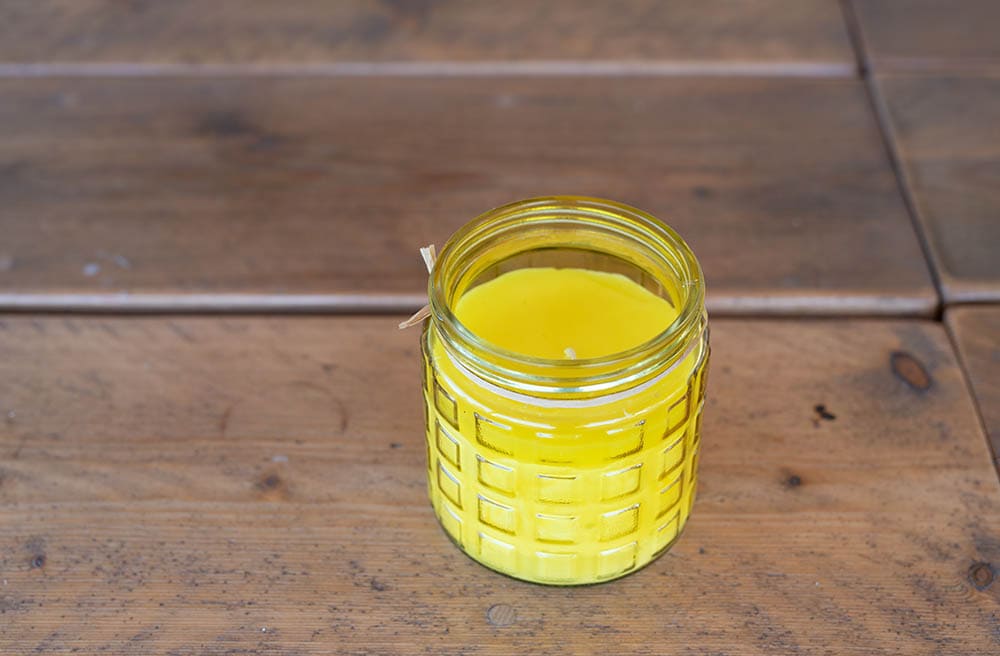 Citronella candle in a glass jar on a wooden table