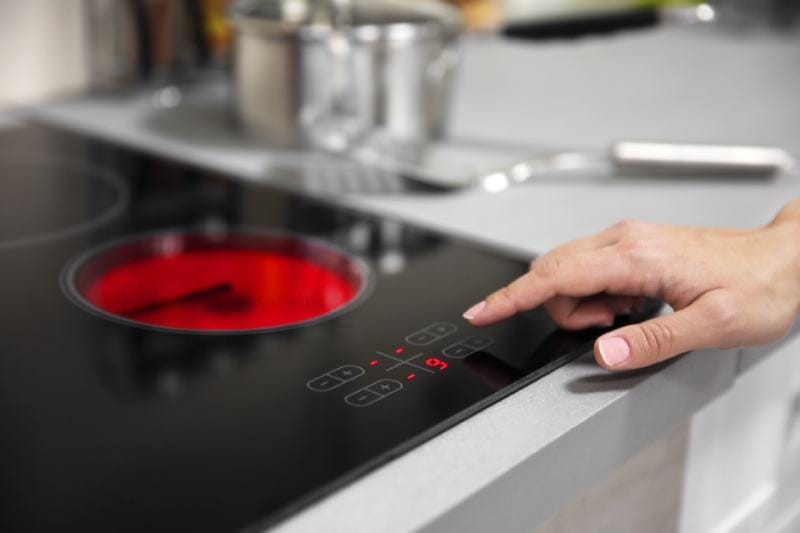 Female hand turns on electric stove closeup
