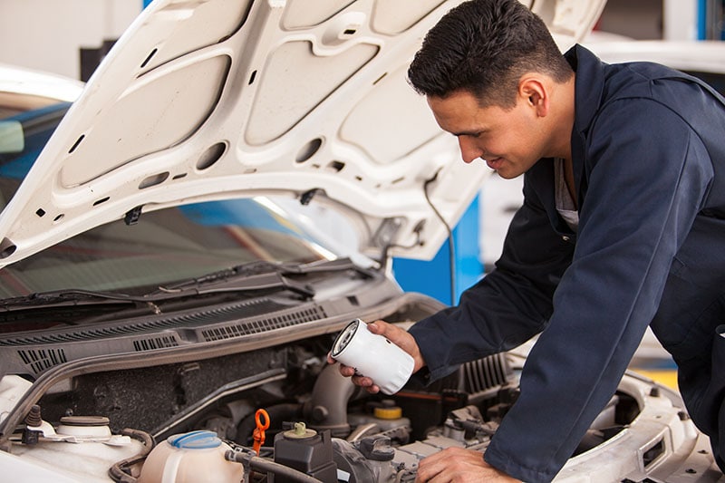 Mechanic changing the oil filter of a car at an auto shop
