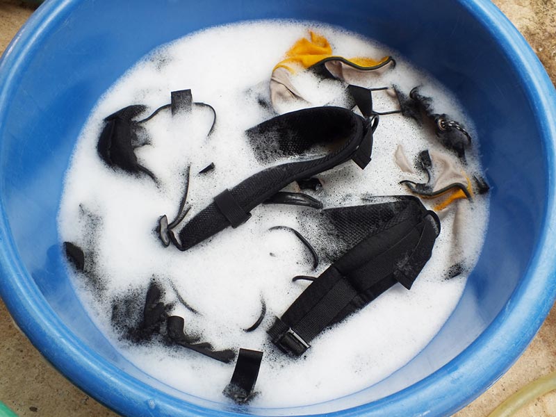backpacks soak in water with detergent in blue basin