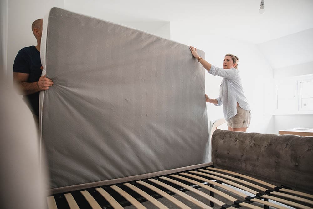 couple moving and carrying a mattress
