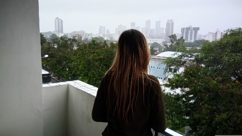 girl smelling rain on balcony before a storm hits