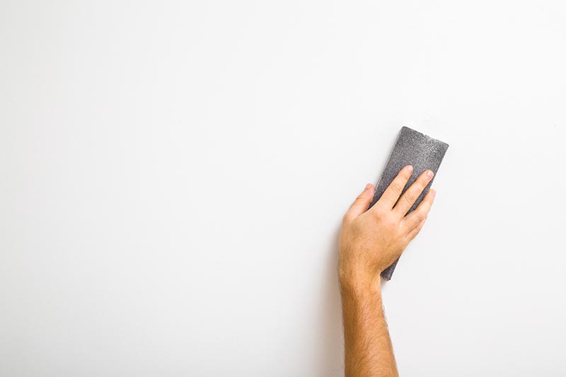 hand sanding white wall