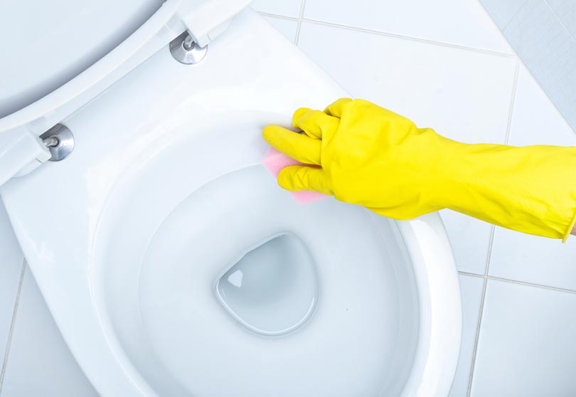 hands in yellow gloves cleaning the toilet