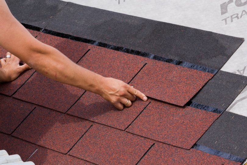 man installing asphalt shingles