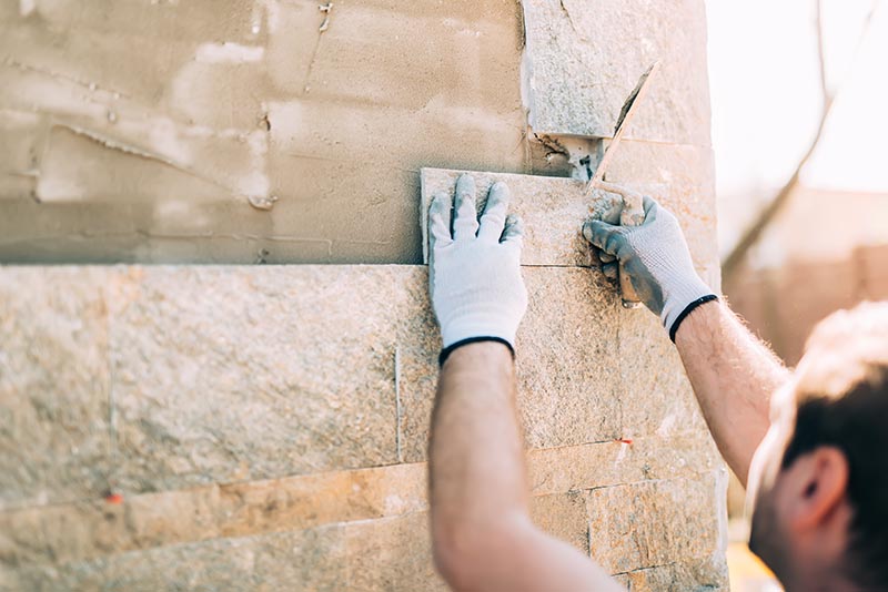 man installing travertine tiles on the wall