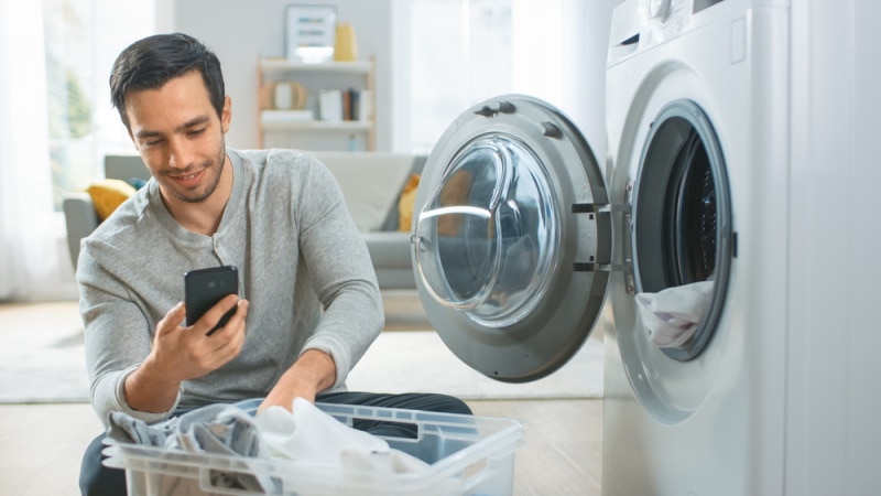 man using phone near washing mac