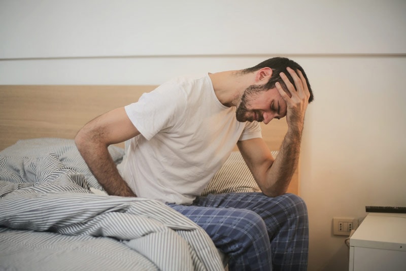 man with a headache on the bed